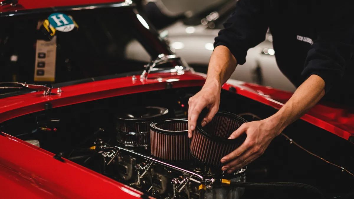 person installing a car engine air filter