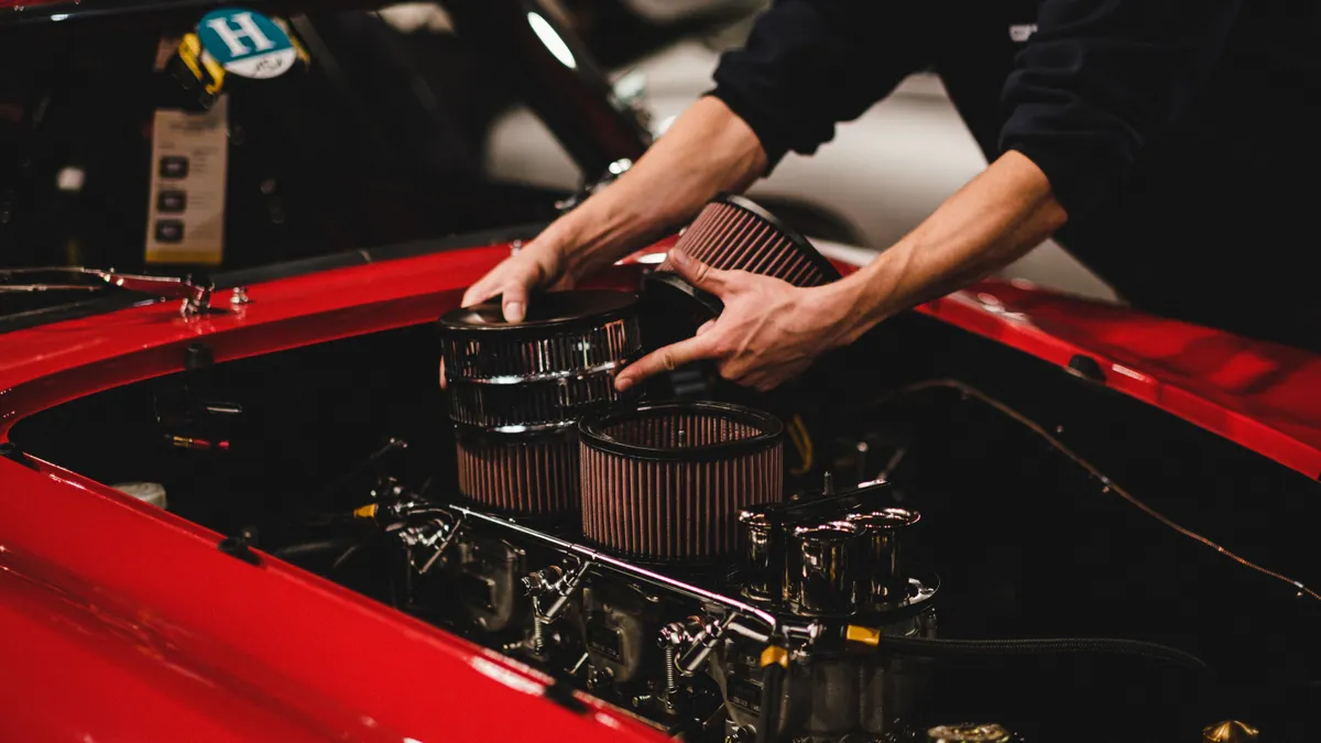 person fitting an engine air filter into a car