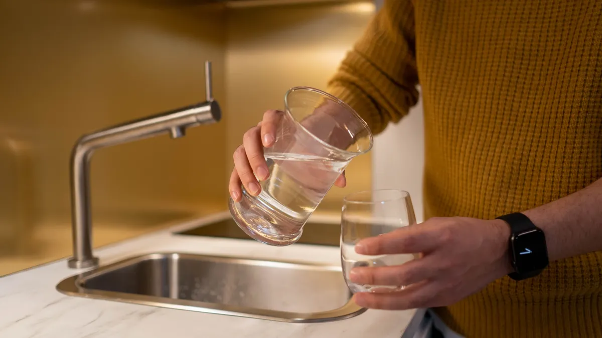 Person pouring water at a kitchen sink