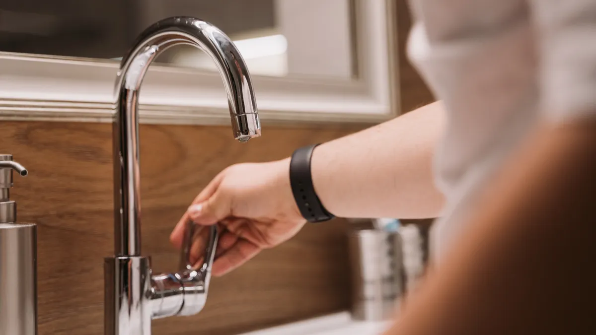 Hand turning on a kitchen faucet