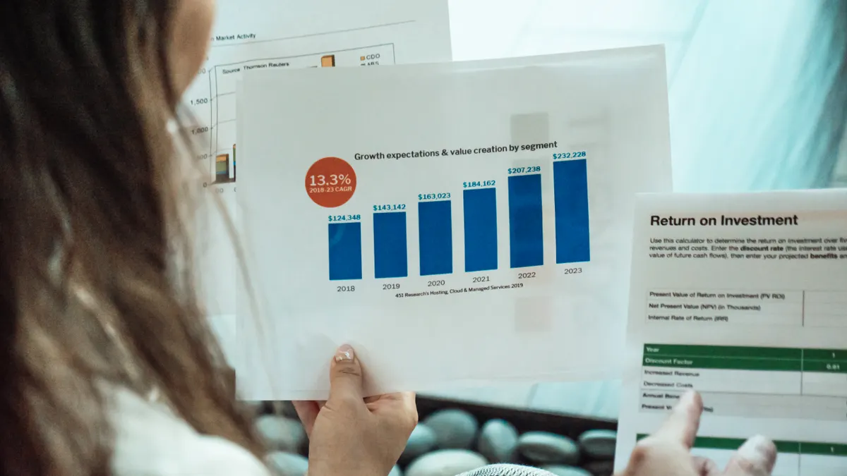 Person holding printed bar charts and a business report